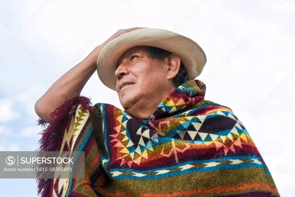 Senior man wearing poncho and hat while looking away