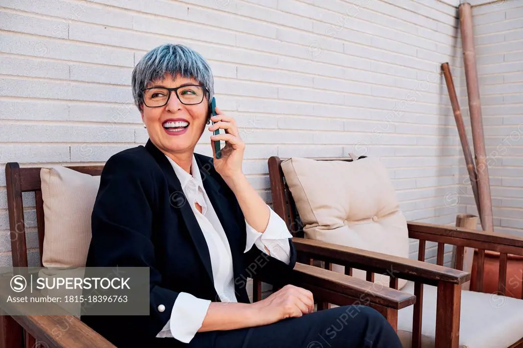 Businesswoman looking away while talking on smart phone at backyard