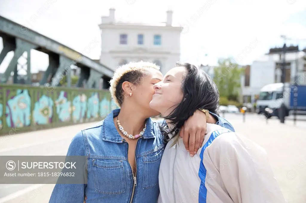 Lesbian woman kissing girlfriend during sunny day