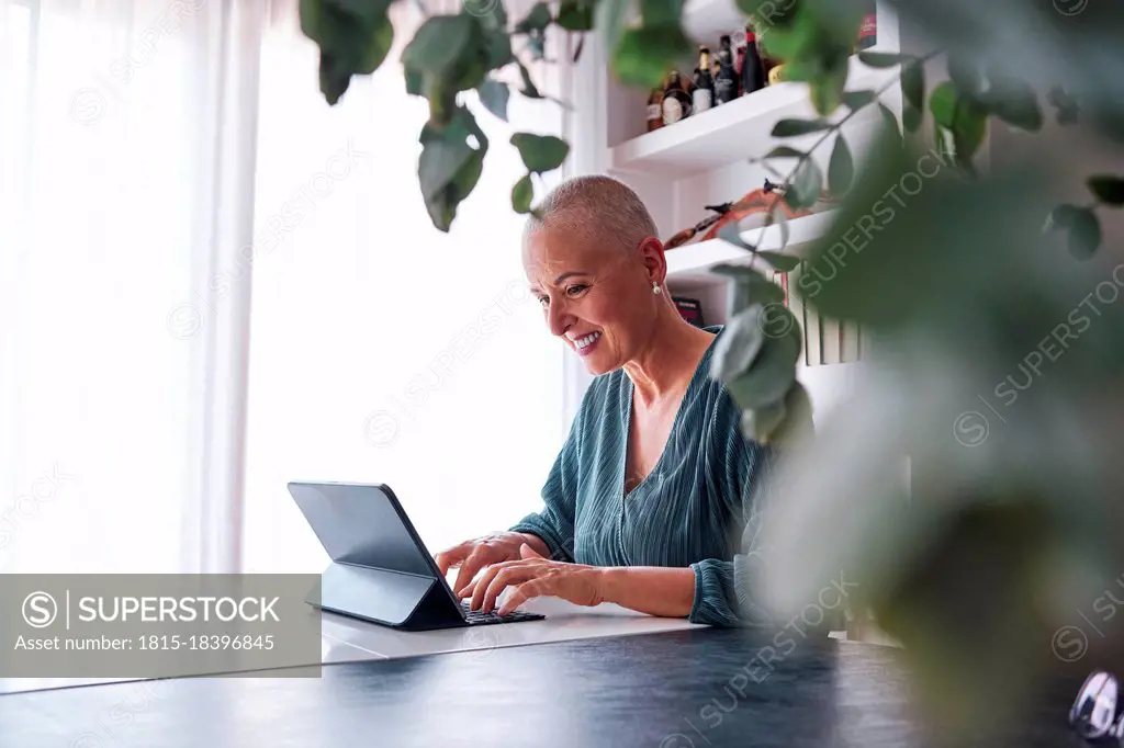 Smiling mature woman using digital tablet in living room at home