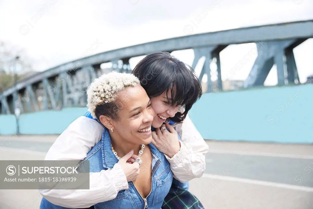 Happy woman enjoying piggyback ride from girlfriend