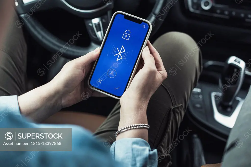 Woman accessing bluetooth on mobile phone in car