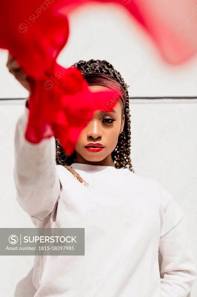 Confident young woman with red scarf in front of white wall