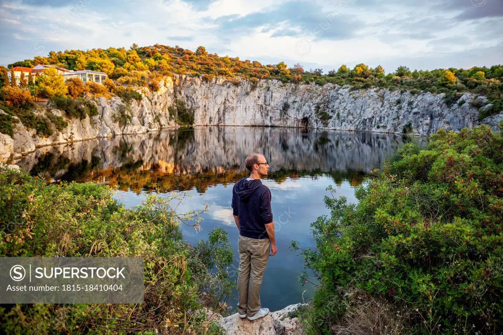 Man standing on rock formation while looking at Lake Dragon's Eye, Rogoznica, Croatia