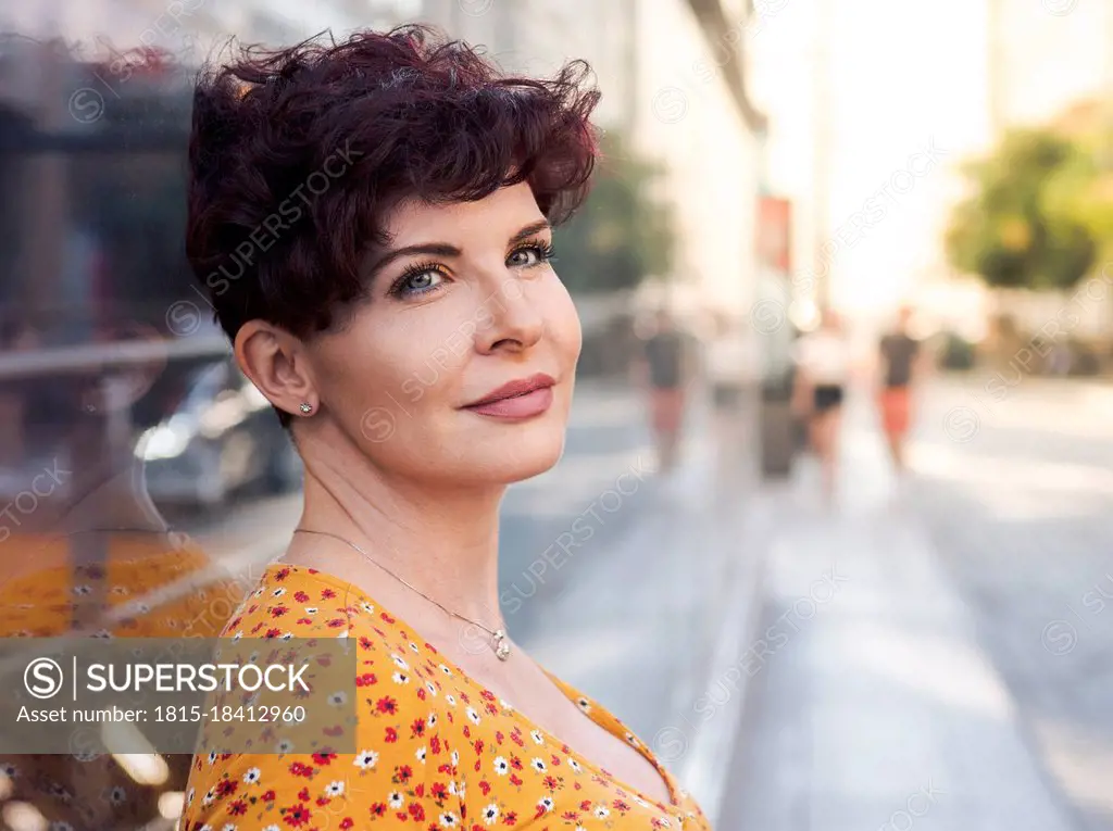 Mature woman with short hair contemplating while leaning on wall