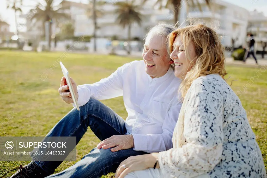 Happy mature couple doing video call through digital tablet during sunny day