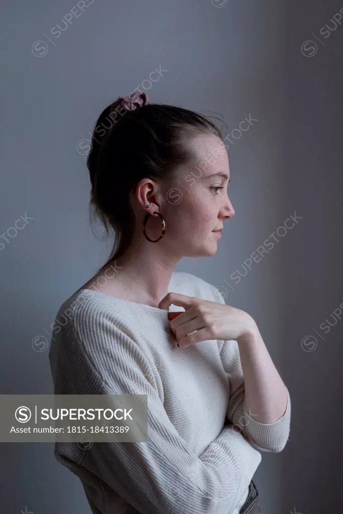 Young woman standing by white wall at home