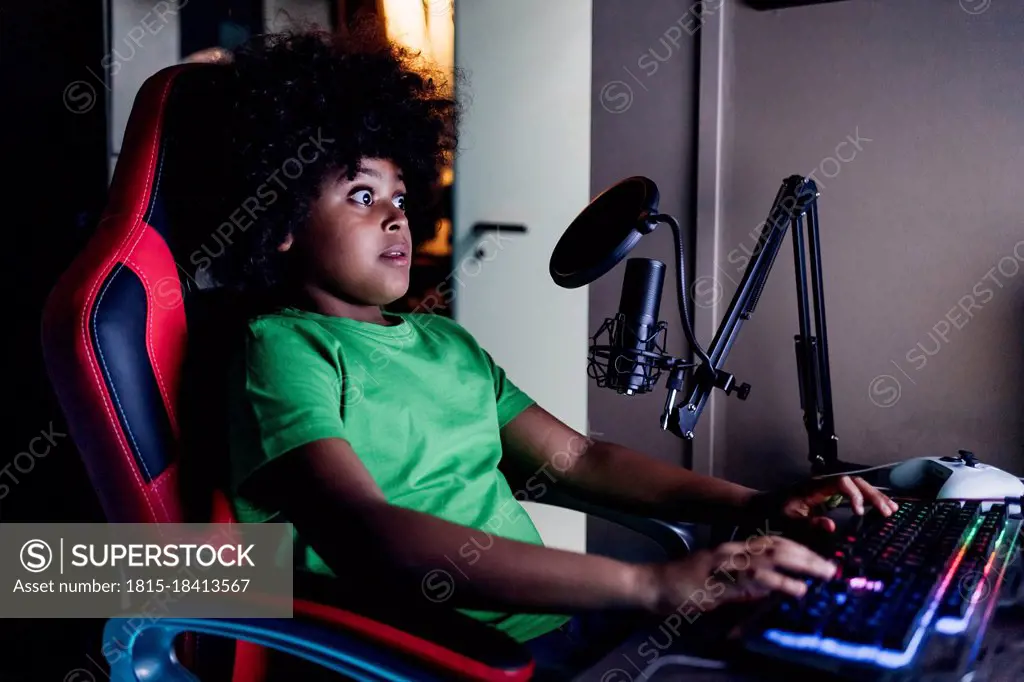 Shocked boy playing video game on computer at home