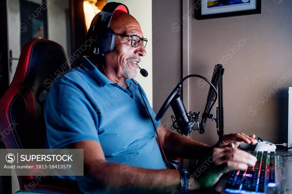 Senior man doing online streaming while playing video game at home