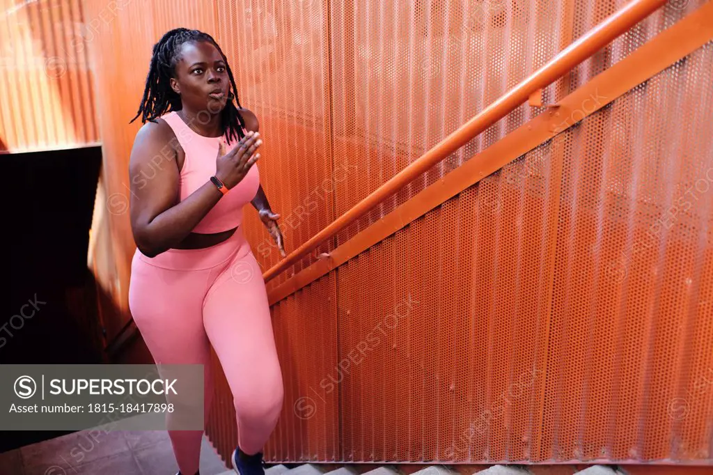 Plus size woman in sports clothing running on staircase