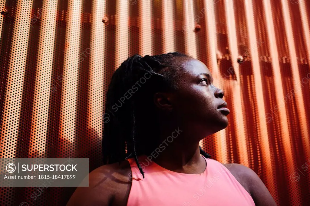 Young woman looking away in front of corrugated brown wall