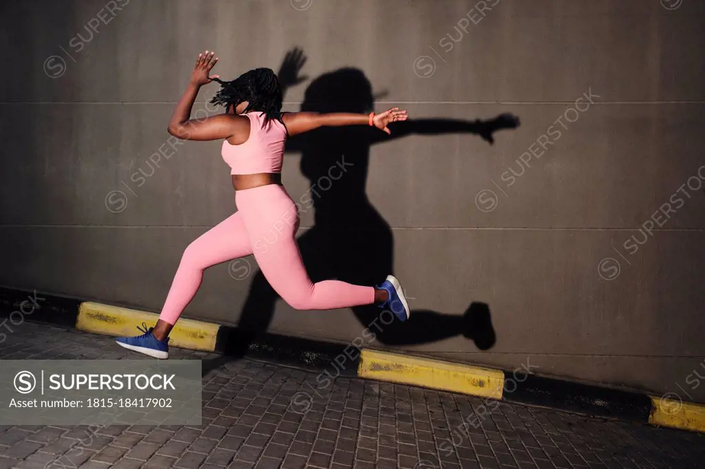 Plus size young woman jumping over road