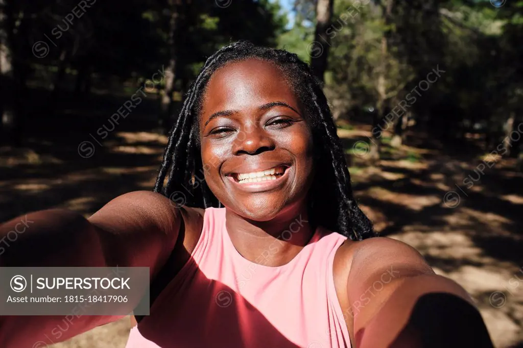 Happy young woman taking selfie in sunlight