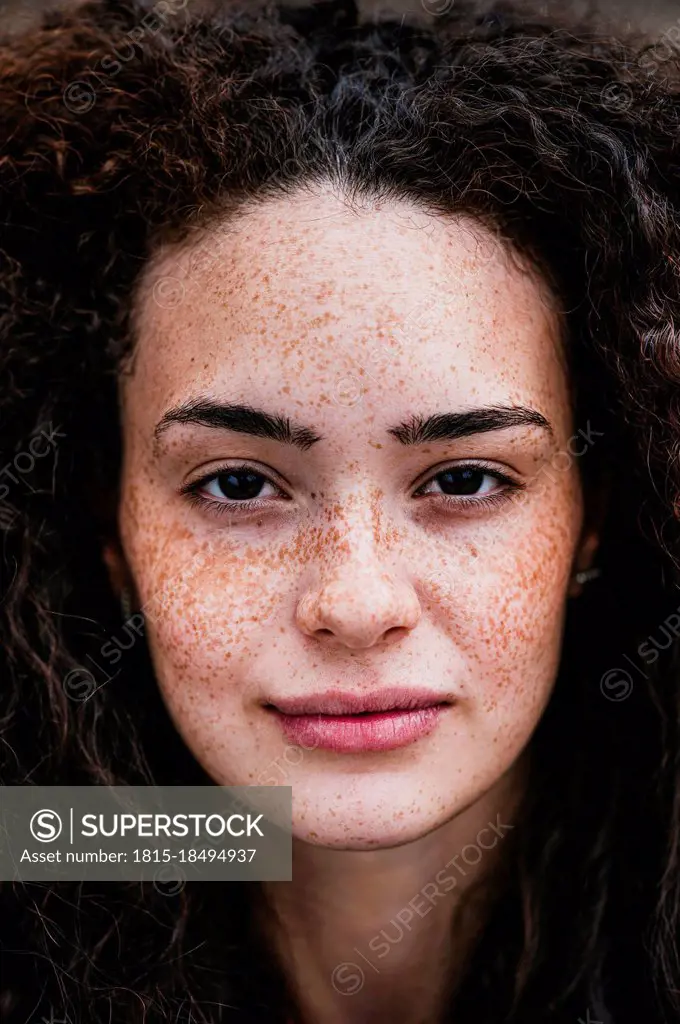 Beautiful young curly haired woman with freckles