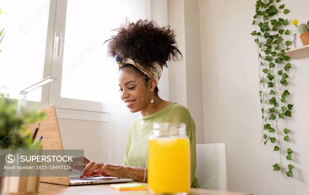 Smiling young businesswoman working on laptop in green house