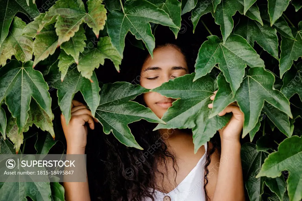 Woman with eyes closed amidst leaves