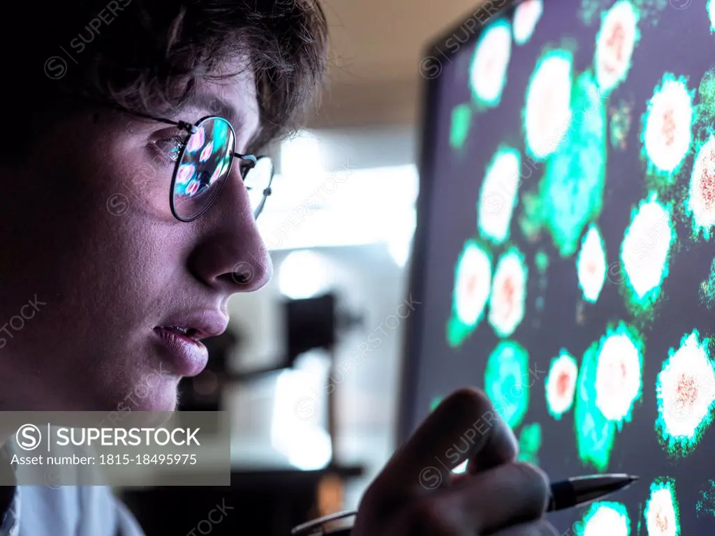 Male scientist researching on biological cell on computer screen in laboratory