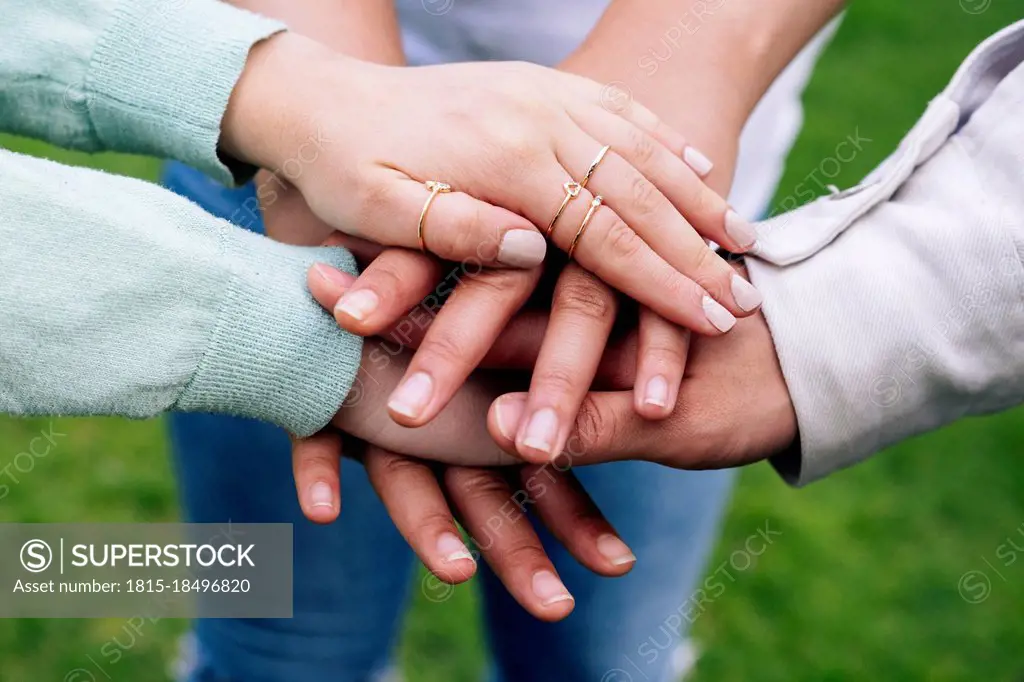 Male and female friends stacking hands