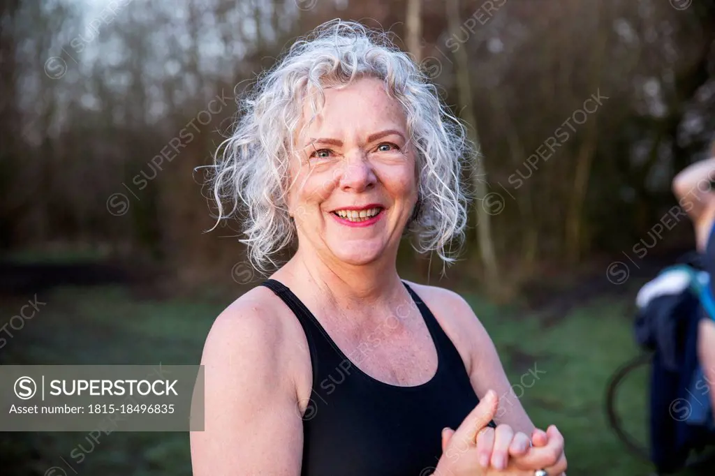 Smiling senior woman with hands clasped in nature