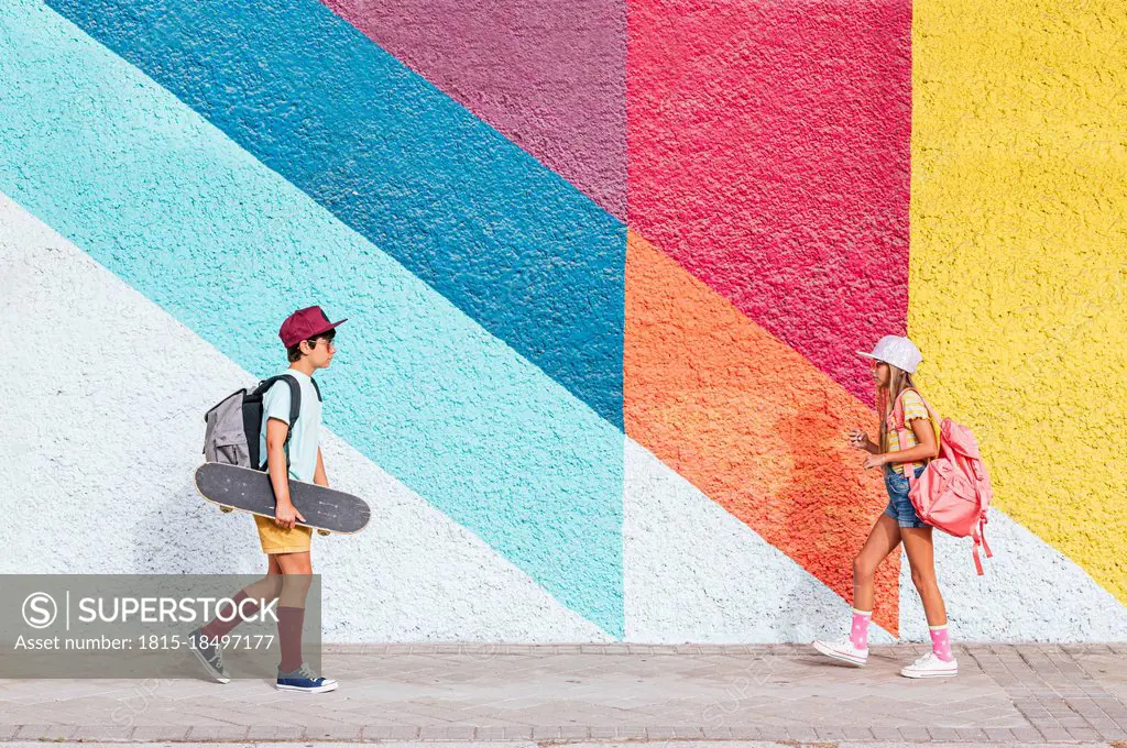 Girl and boy with backpacks walking on footpath