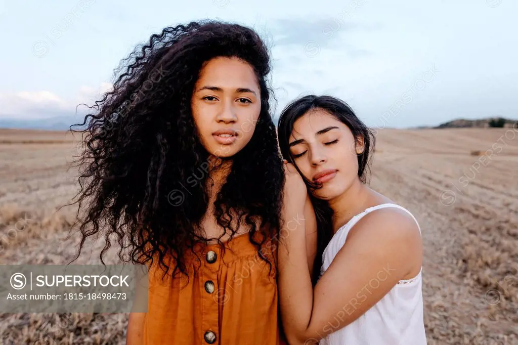 Woman leaning on woman shoulder while standing at field