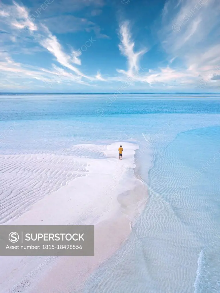 Aerial view of lone man standing on sandy coastal beach of Thulusdhoo island