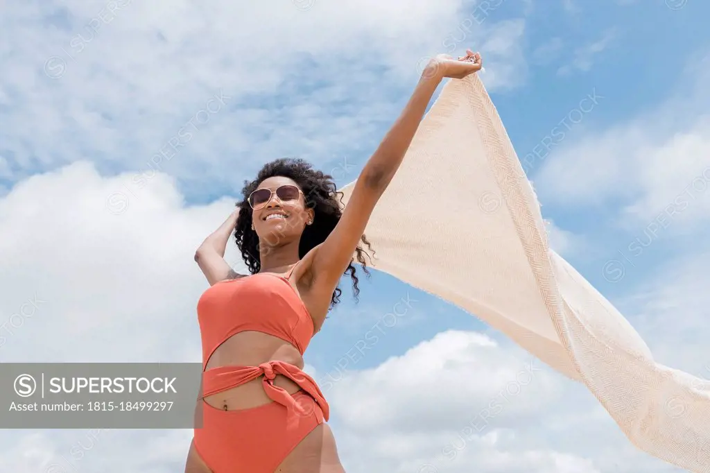 Young woman holding beach towel on sunny day