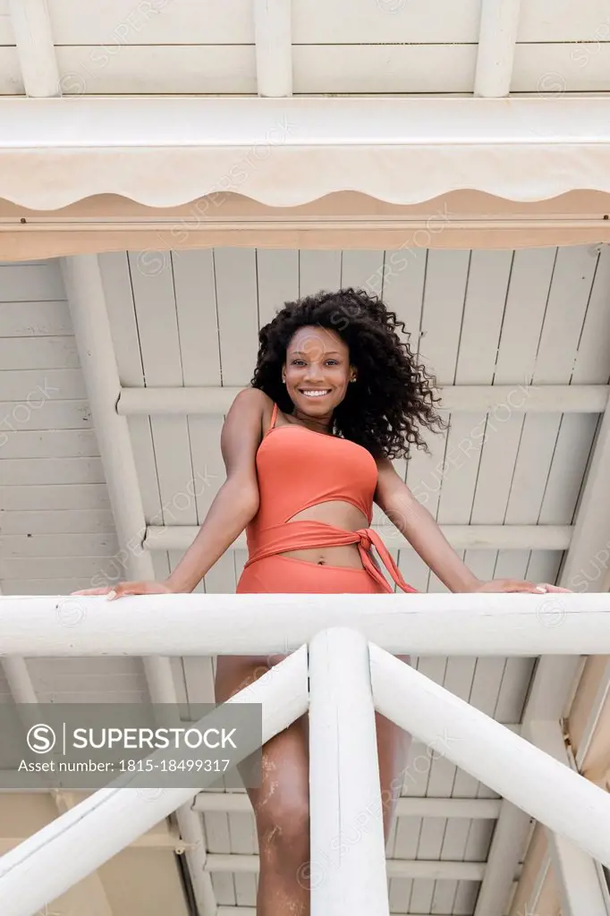 Smiling woman leaning on railing at lifeguard hut