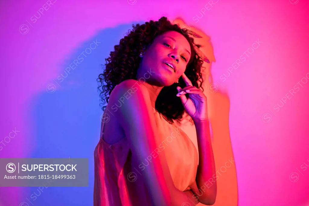 Young woman with head cocked against colored background