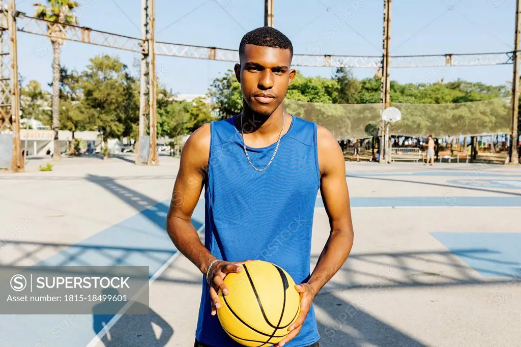 Male basketball player holding basketball at sports court