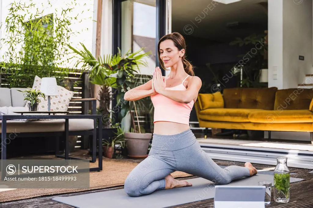 Woman with hands clasped practicing yoga on terrace