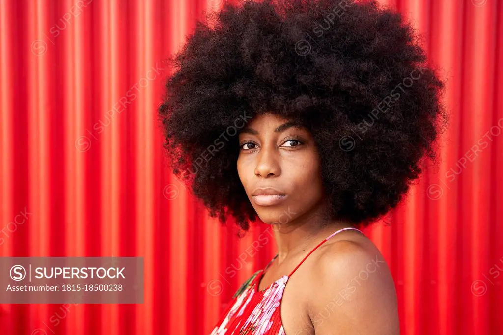 Afro young woman by red corrugated wall