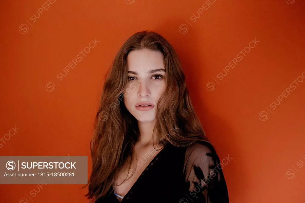 Beautiful young woman with long brown hair against red background