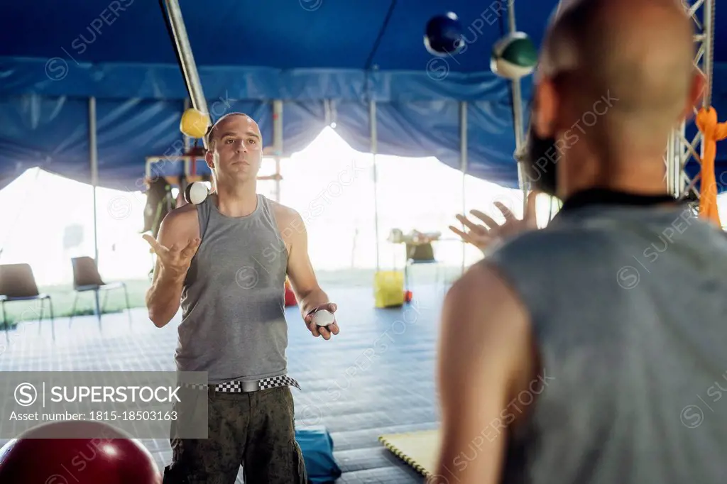 Male acrobats practicing while juggling balls in circus