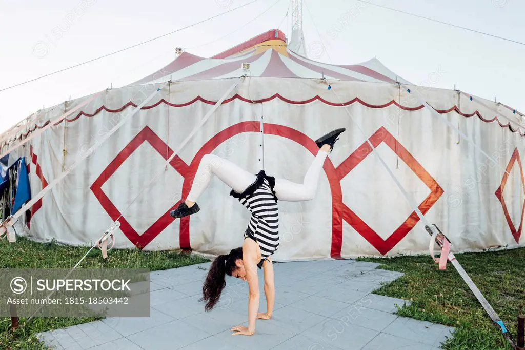 Female acrobat doing handstand on footpath