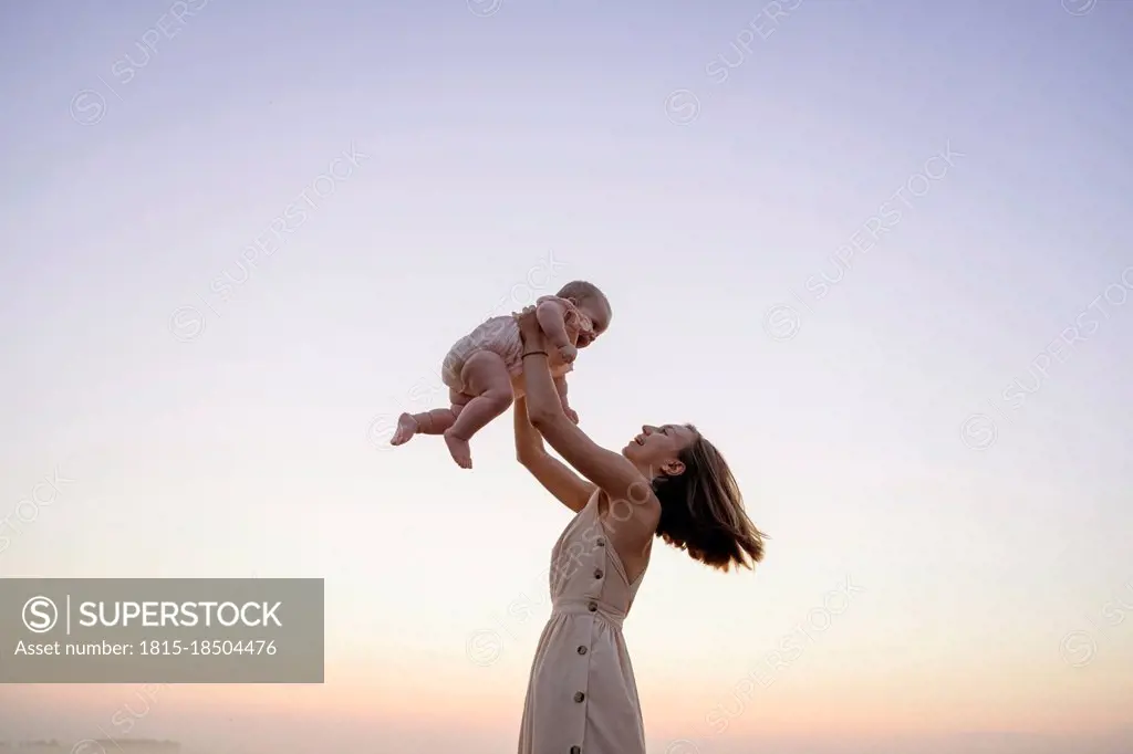 Happy mother playing with daughter during sunset