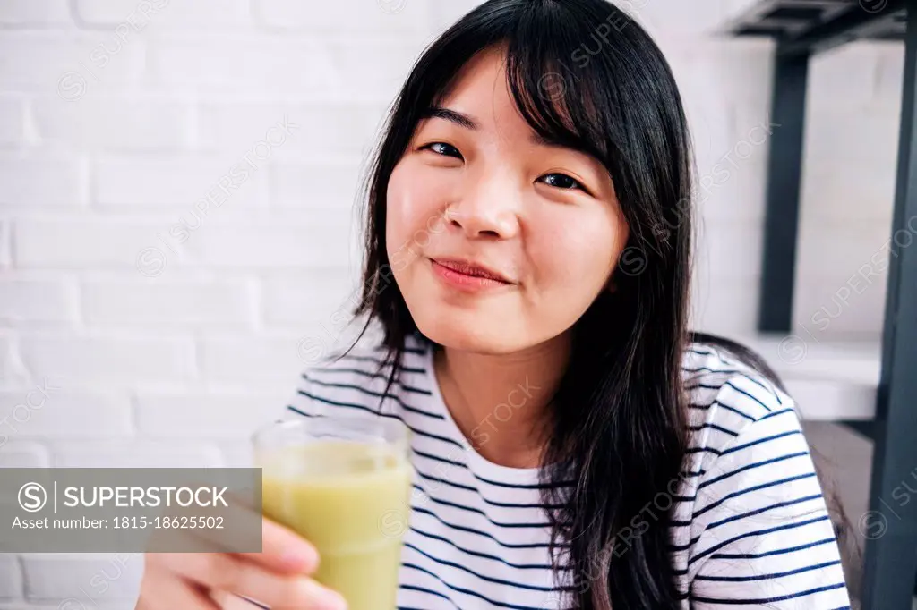 Young woman holding healthy smoothie at home