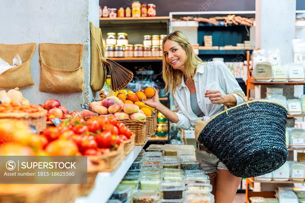 Woman carrying basket while buying fruits at supermarket