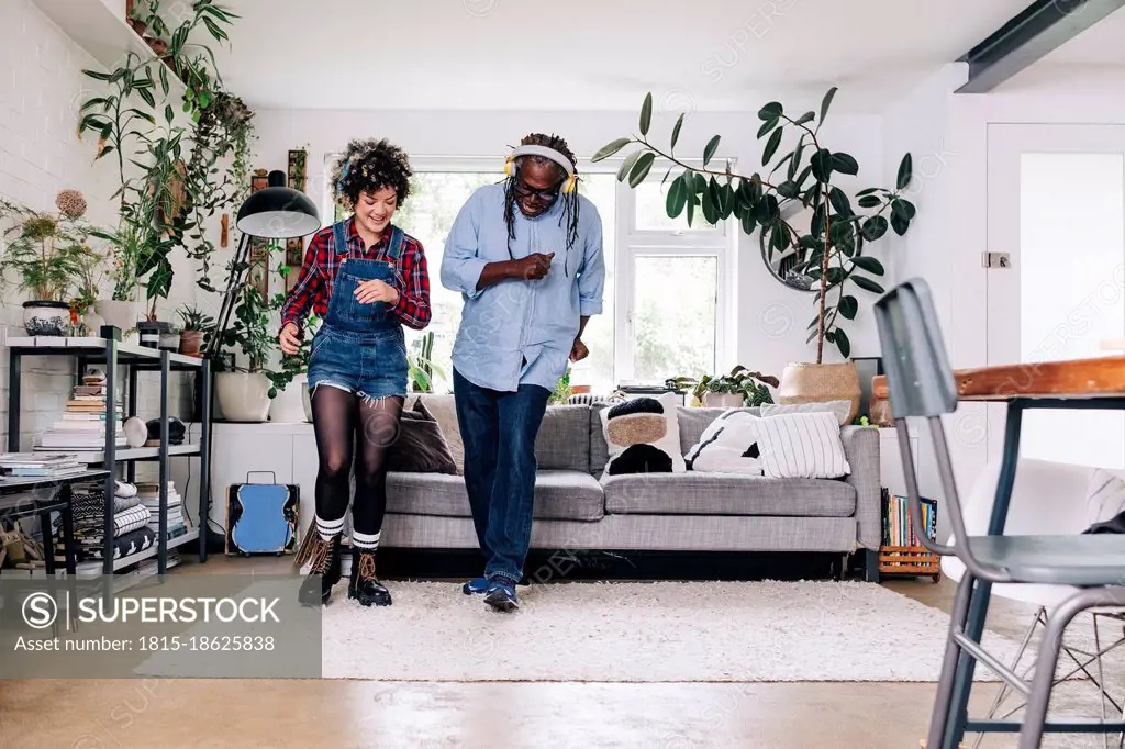 Happy father and daughter dancing together in living room