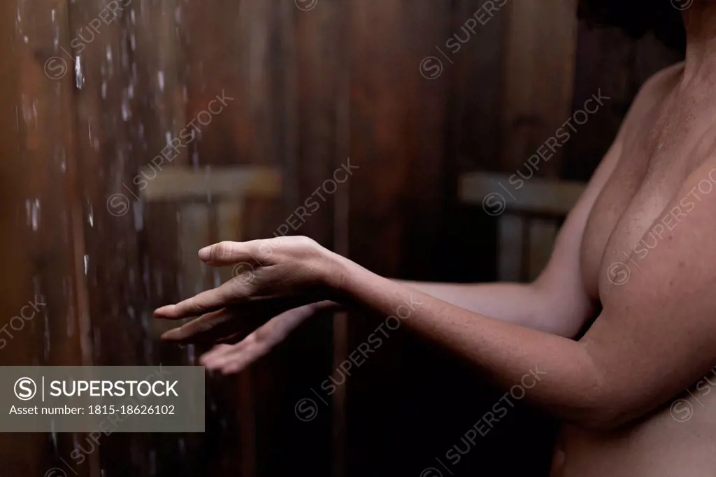 Shirtless woman taking shower in cabana