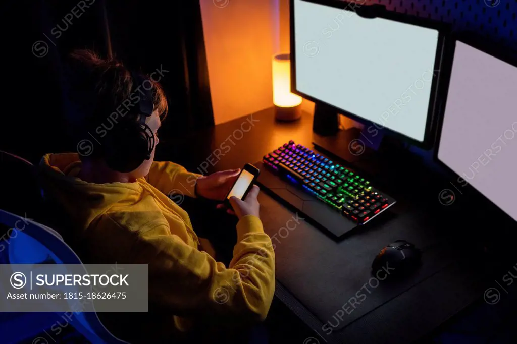 Boy using smart phone while playing video game on table at home