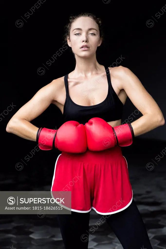 Confident female athlete wearing boxing gloves standing at basement