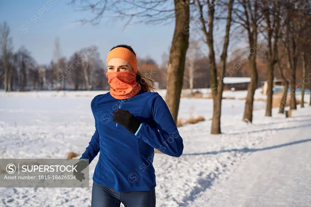 Woman wearing gaiter face mask while running during winter