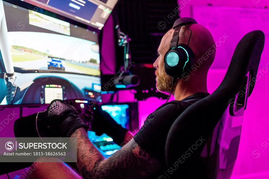 Mid adult male gamer playing video game at studio