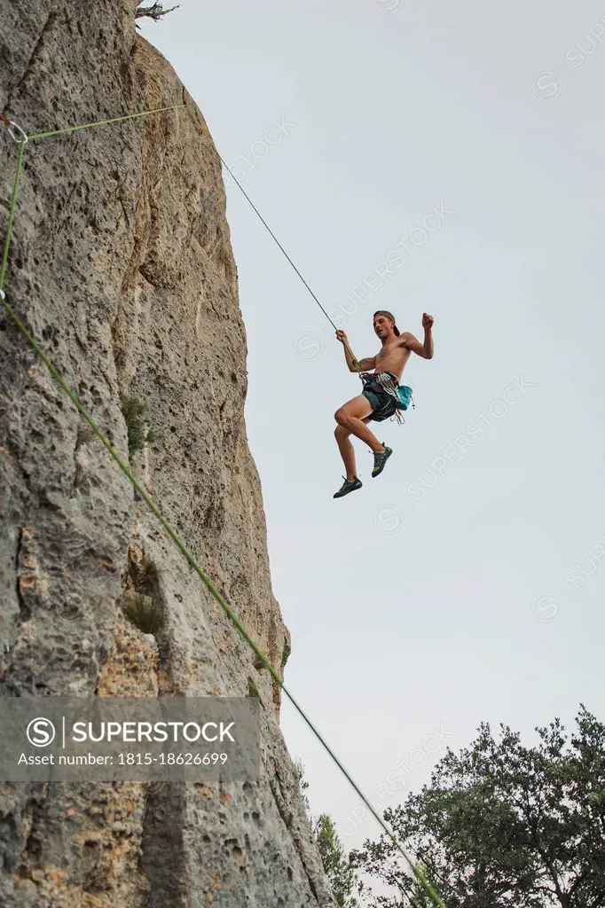 Male climber hanging through rope on rock mountain