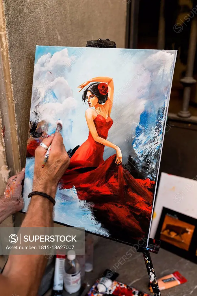 Creative male street artist painting female on canvas