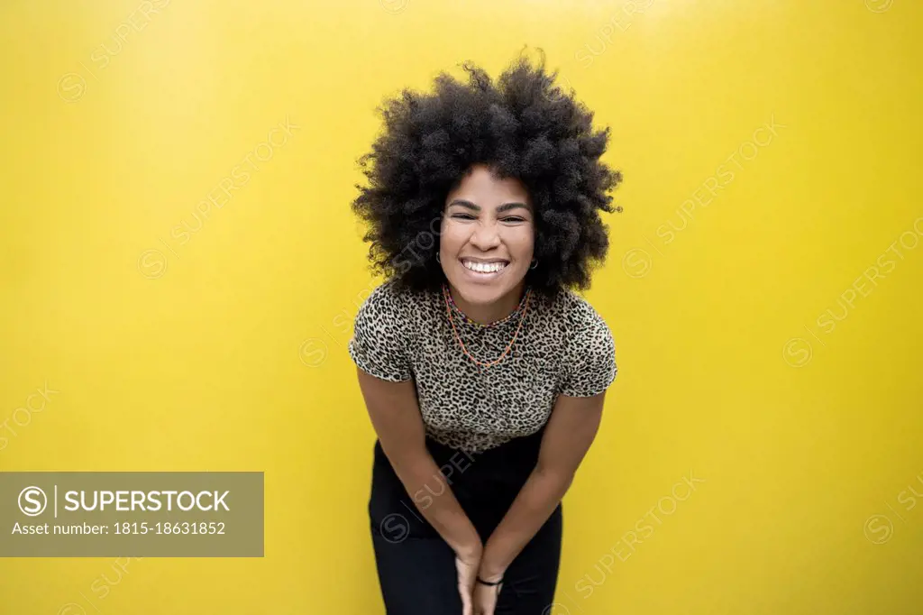 Afro woman smiling in front of yellow wall