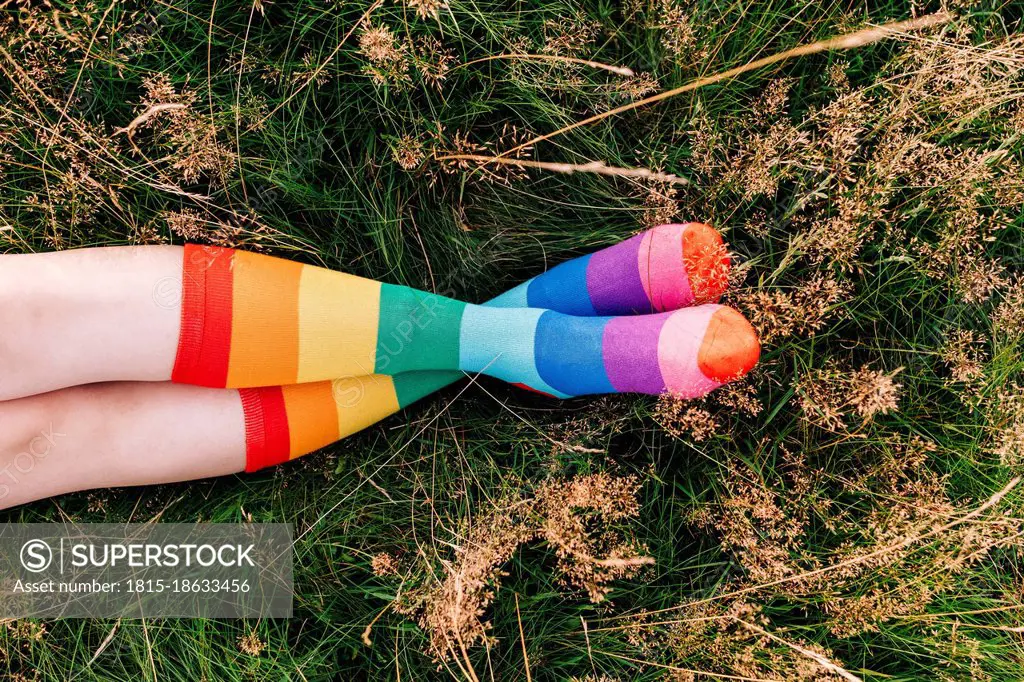 Woman wearing rainbow socks with legs crossed at ankle on grass