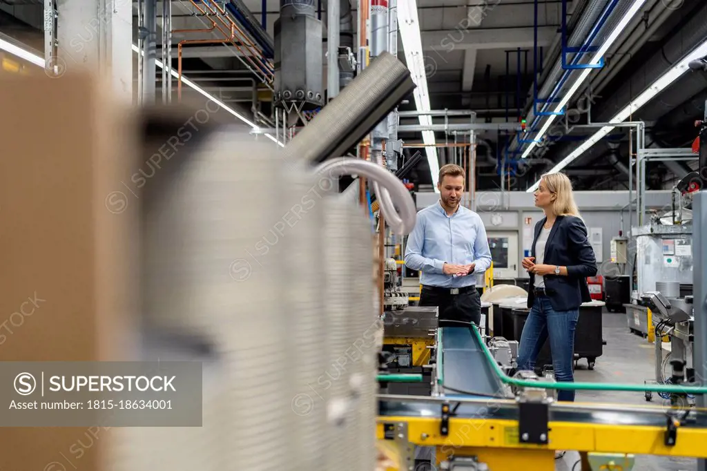 Female manager standing with male coworker at production line