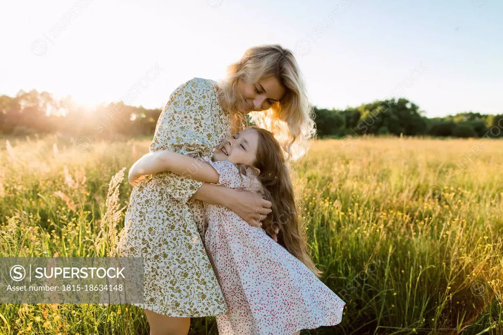 Smiling mother embracing daughter at meadow